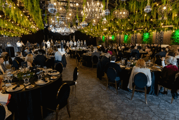 O vedere largă a unei săli de bal cu mese cu fețe de masă negre și oameni așezați.