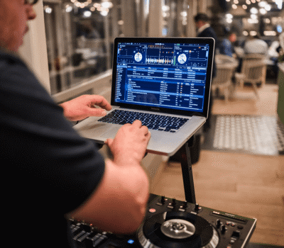DJ folosind un laptop MacBook Pro cu software audio.