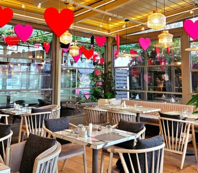 Interiorul unui restaurant cu decor de Ziua Îndrăgostiților, cu inimi roșii și roz atârnate.